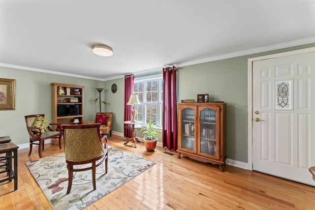 living room featuring light wood finished floors, baseboards, and ornamental molding