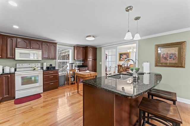 kitchen featuring a kitchen bar, light wood-type flooring, white appliances, ornamental molding, and a sink