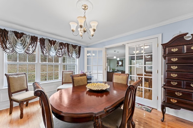 dining room with french doors, a notable chandelier, crown molding, and light wood-style floors