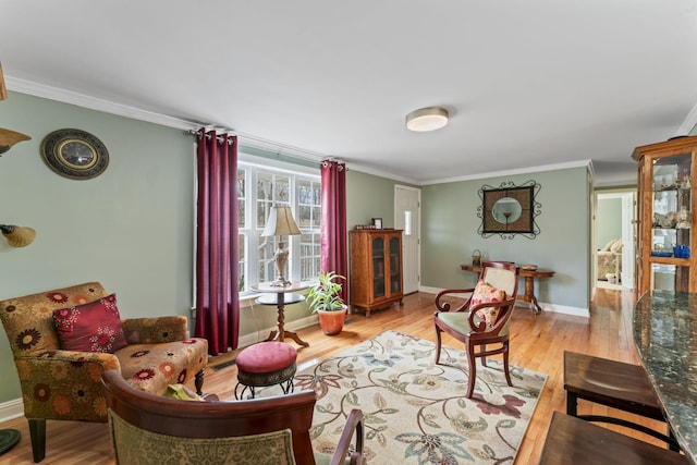 sitting room with baseboards, crown molding, and wood finished floors
