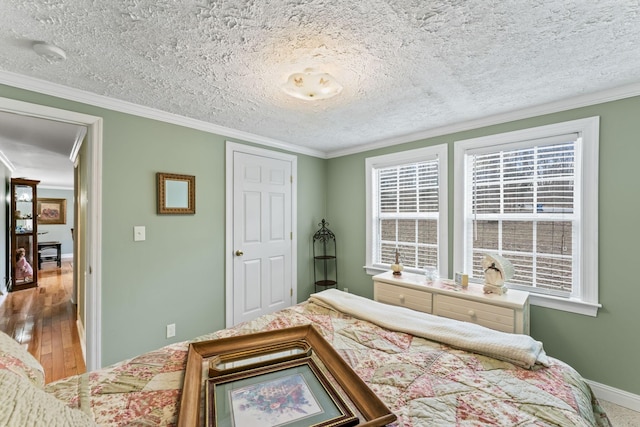 bedroom featuring baseboards, a textured ceiling, wood finished floors, and crown molding