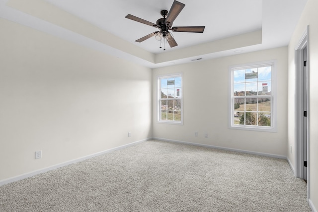 unfurnished bedroom with baseboards, a tray ceiling, and multiple windows