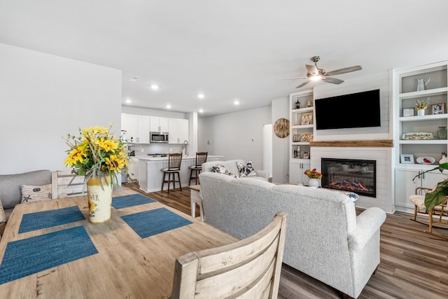 living area featuring a large fireplace, wood finished floors, recessed lighting, and a ceiling fan