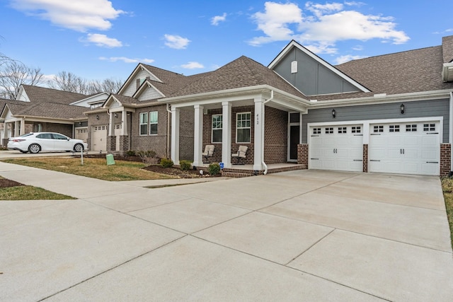 view of front of house with roof with shingles, concrete driveway, an attached garage, brick siding, and a porch