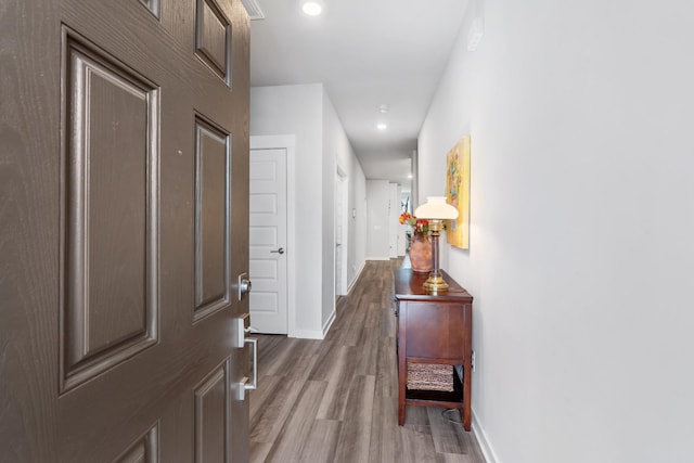 hall featuring recessed lighting, baseboards, and wood finished floors