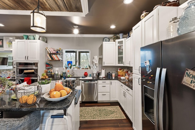kitchen with backsplash, appliances with stainless steel finishes, dark wood-type flooring, dark countertops, and ornamental molding