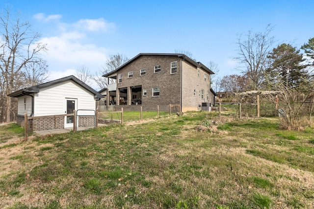 rear view of house with a lawn, brick siding, fence, and an outdoor structure