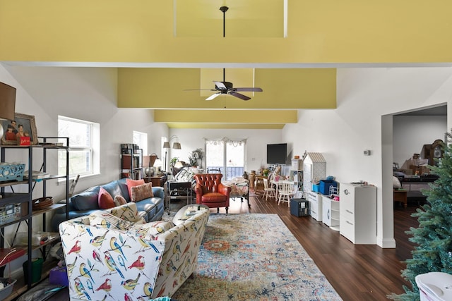 living area with dark wood-style flooring, ceiling fan, and a towering ceiling
