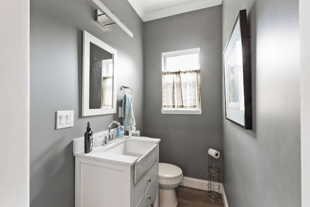 bathroom featuring toilet, vanity, wood finished floors, baseboards, and ornamental molding