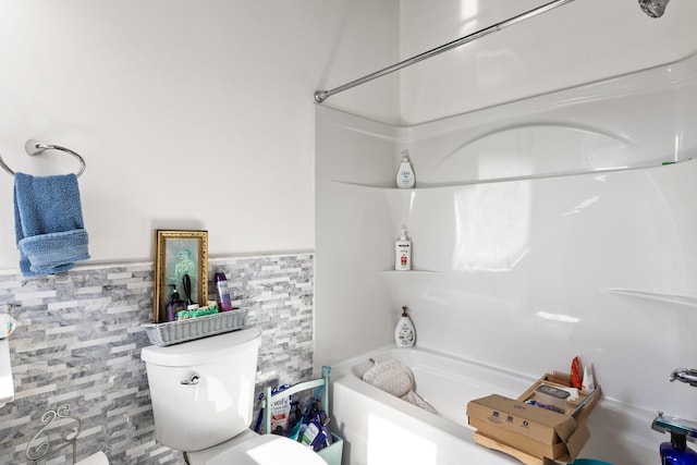 full bath featuring tub / shower combination, wainscoting, toilet, and tile walls
