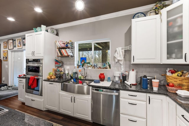 kitchen with white cabinetry, ornamental molding, a sink, and stainless steel appliances