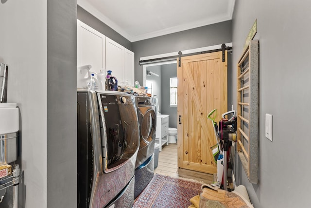 clothes washing area featuring washing machine and dryer, ornamental molding, light wood-type flooring, and cabinet space