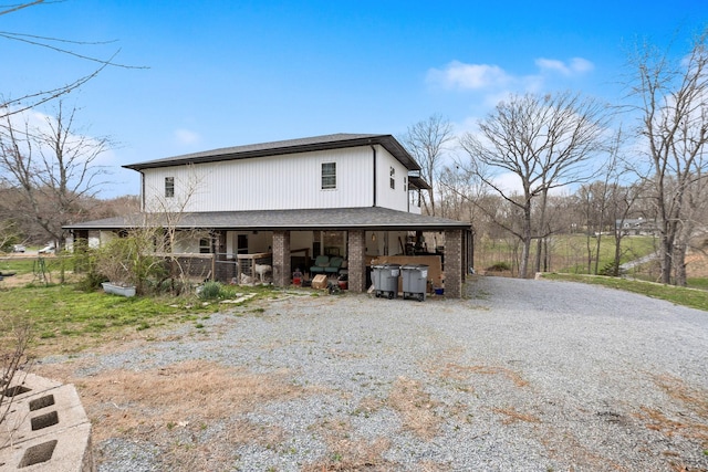 exterior space featuring gravel driveway and brick siding
