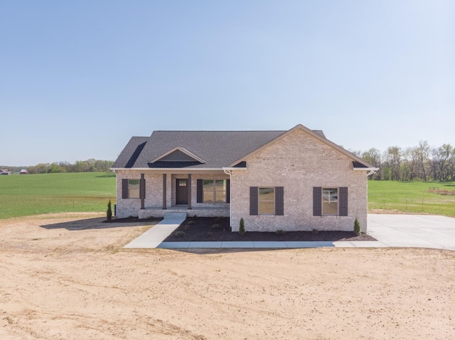 view of front of home with roof with shingles, a front yard, and brick siding