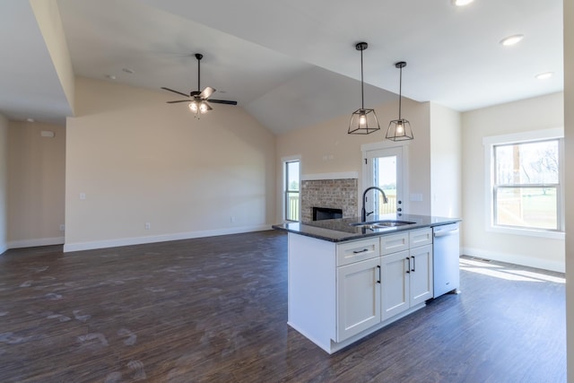 kitchen featuring a fireplace, white cabinets, dishwasher, a sink, and open floor plan