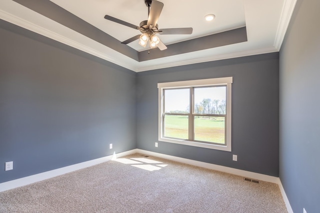 spare room with carpet, ornamental molding, visible vents, a raised ceiling, and baseboards