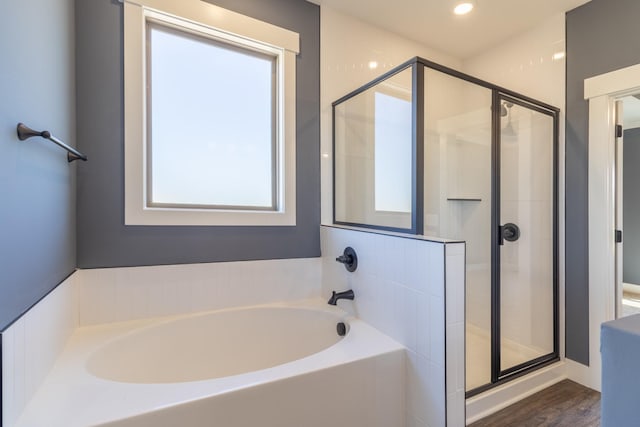 bathroom with a stall shower, a garden tub, wood finished floors, and recessed lighting