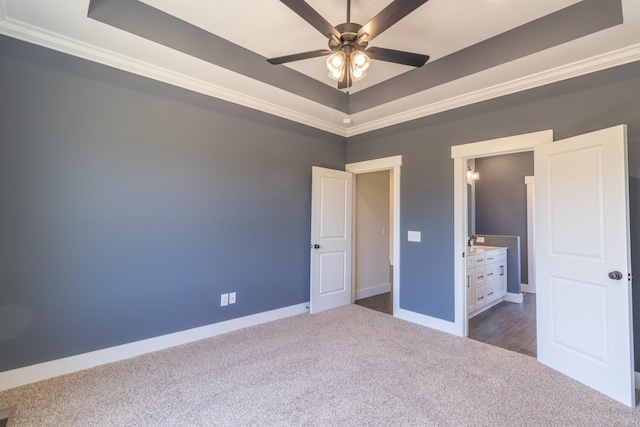 unfurnished bedroom with baseboards, dark carpet, crown molding, and a raised ceiling