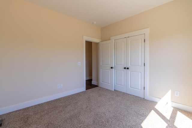 unfurnished bedroom featuring carpet, visible vents, a closet, and baseboards