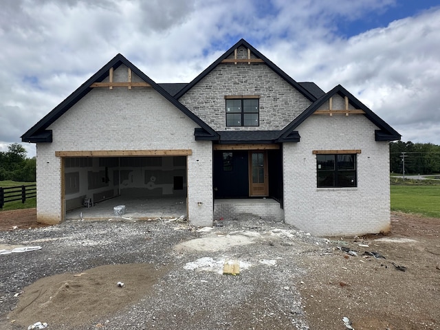 view of front of property featuring brick siding, driveway, fence, and a garage