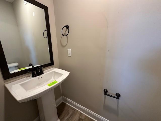 half bath featuring baseboards and wood finished floors
