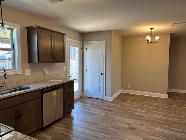 kitchen featuring a notable chandelier, a sink, pendant lighting, wood finished floors, and dishwasher