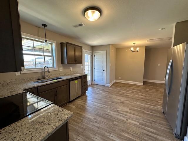 kitchen with stainless steel appliances, a chandelier, a sink, light wood-style floors, and visible vents