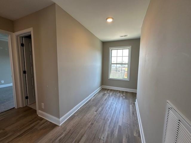 empty room with baseboards, visible vents, and wood finished floors