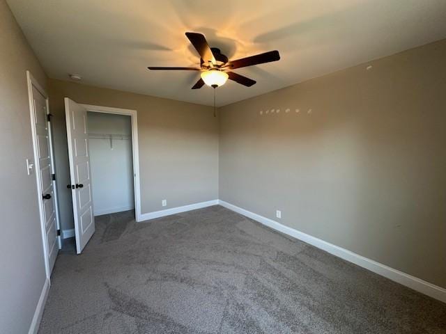 unfurnished bedroom featuring baseboards, dark carpet, and a closet