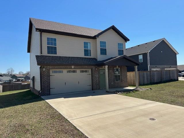 view of front facade featuring an attached garage, brick siding, fence, and a front yard