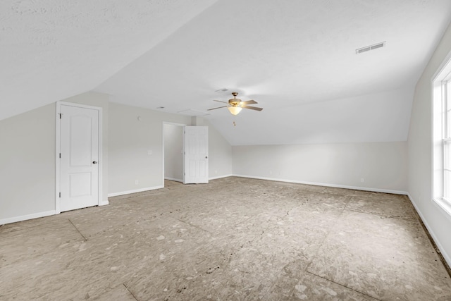 additional living space featuring vaulted ceiling, a ceiling fan, healthy amount of natural light, and baseboards