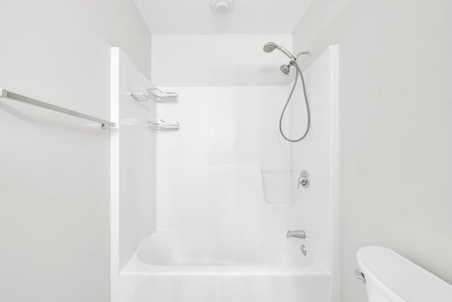 bathroom with toilet, a textured ceiling, and  shower combination