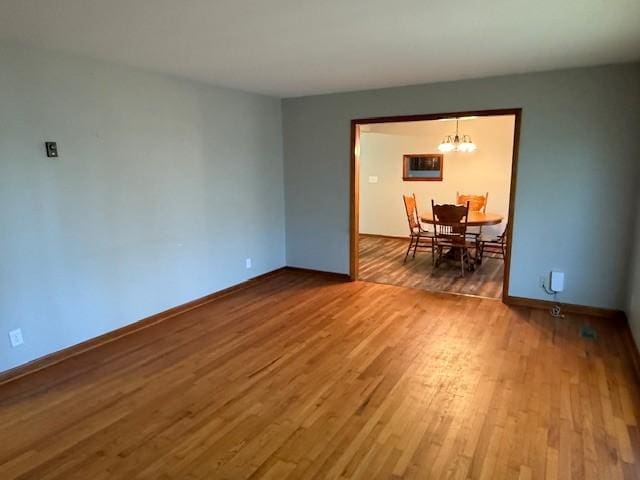 unfurnished dining area with baseboards, an inviting chandelier, and wood finished floors