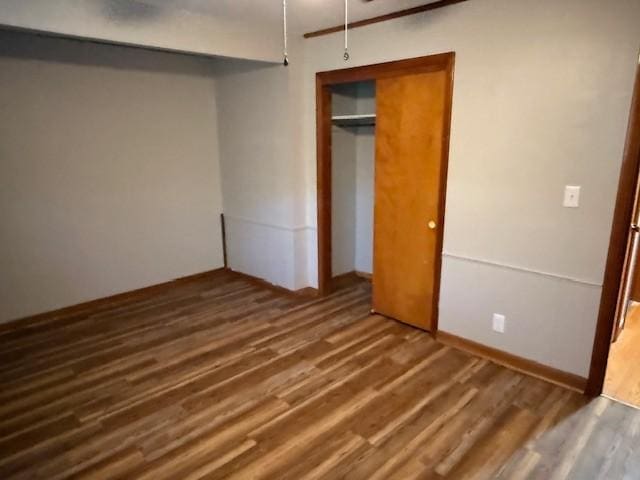 unfurnished bedroom with wood finished floors and a closet