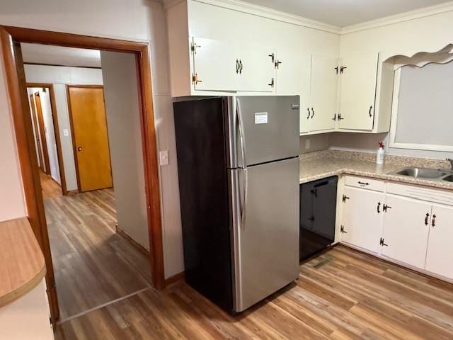 kitchen with freestanding refrigerator, light countertops, white cabinetry, a sink, and light wood finished floors
