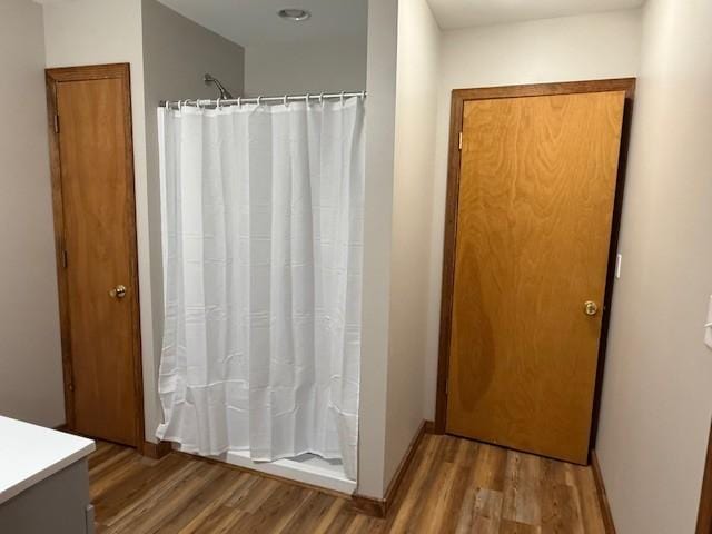 full bath with baseboards, a shower with shower curtain, wood finished floors, and vanity