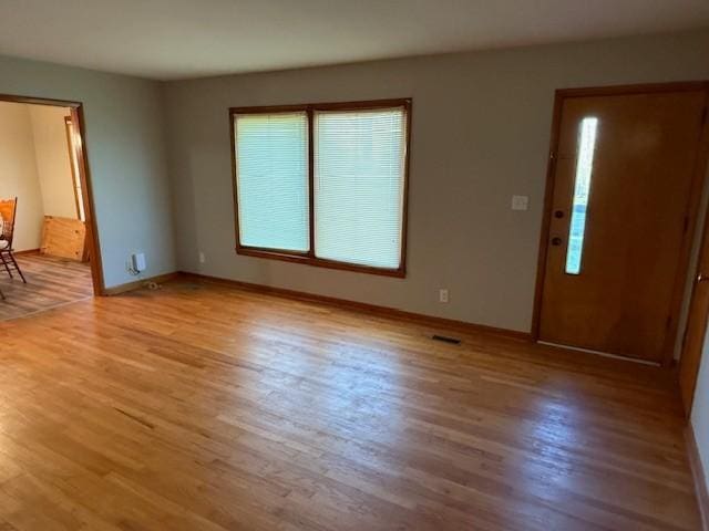 entryway with baseboards, a wealth of natural light, and light wood finished floors