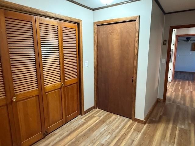 interior space with light wood-type flooring, ornamental molding, and baseboards