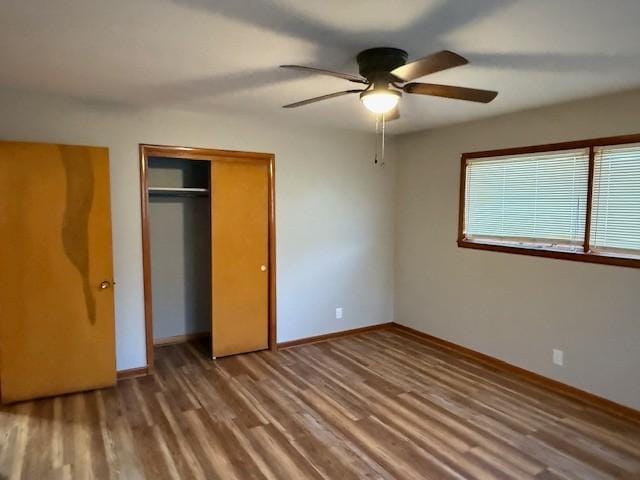 unfurnished bedroom featuring a ceiling fan, baseboards, wood finished floors, and a closet