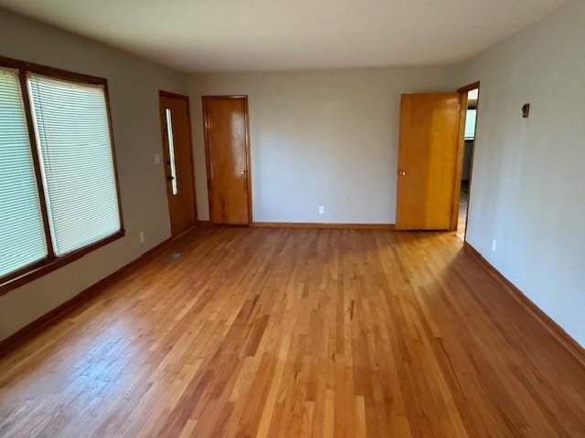 spare room featuring light wood-type flooring, baseboards, and plenty of natural light