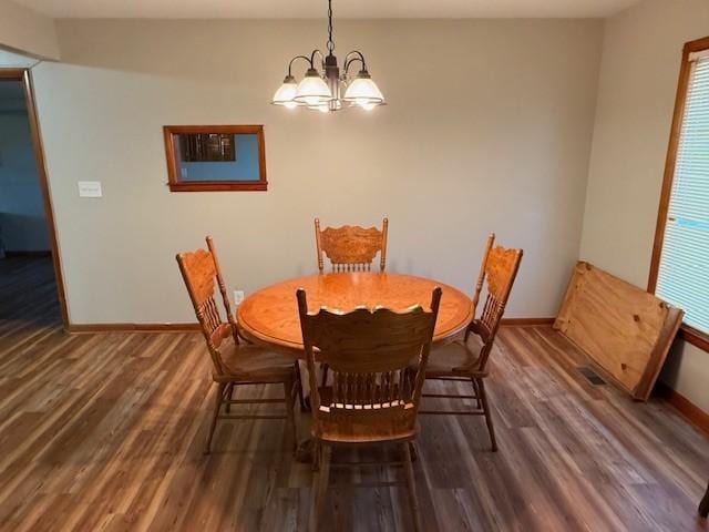 dining space featuring baseboards, wood finished floors, a notable chandelier, and visible vents
