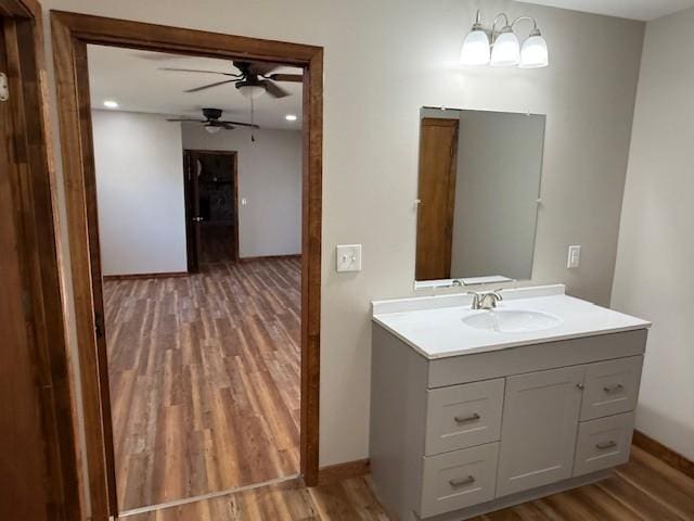 bathroom with baseboards, ceiling fan, wood finished floors, and vanity