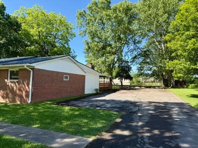 1302 Old Estill Springs Rd, Tullahoma, TN 37388 - view of side of property featuring brick siding, a lawn, asphalt driveway, and a chimney