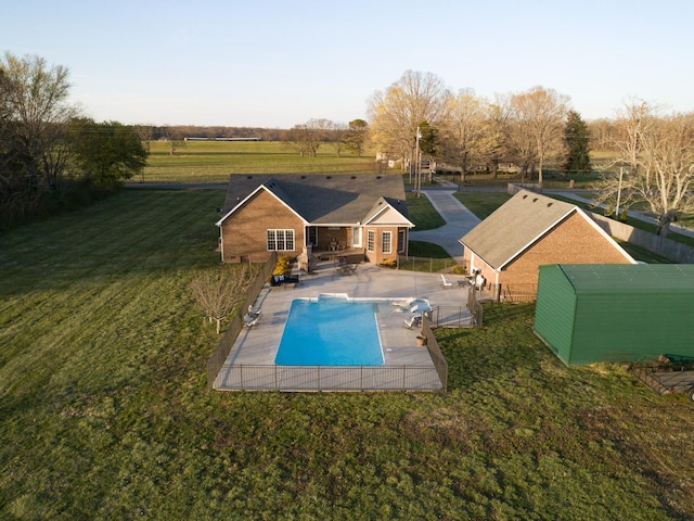 view of pool with fence, a rural view, a lawn, a fenced in pool, and a patio area