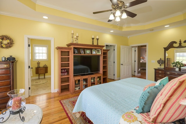 bedroom with a tray ceiling, multiple windows, and light wood-type flooring
