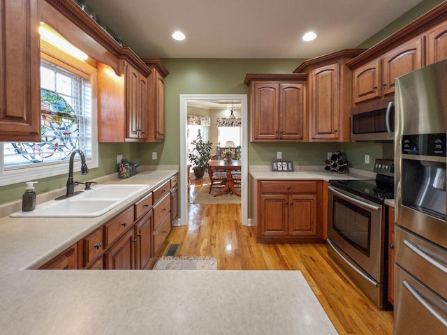kitchen featuring light wood finished floors, a sink, light countertops, and appliances with stainless steel finishes
