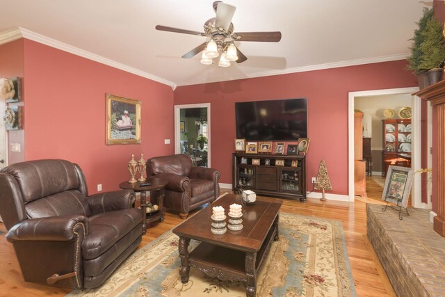 living area featuring baseboards, crown molding, wood finished floors, and a ceiling fan