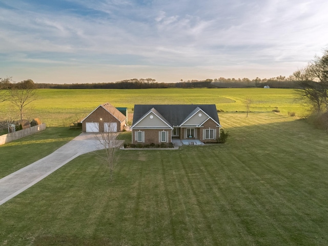 view of front facade featuring a rural view, concrete driveway, and a front yard