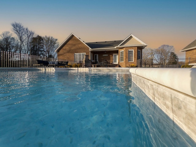 pool at dusk with a fenced in pool and fence