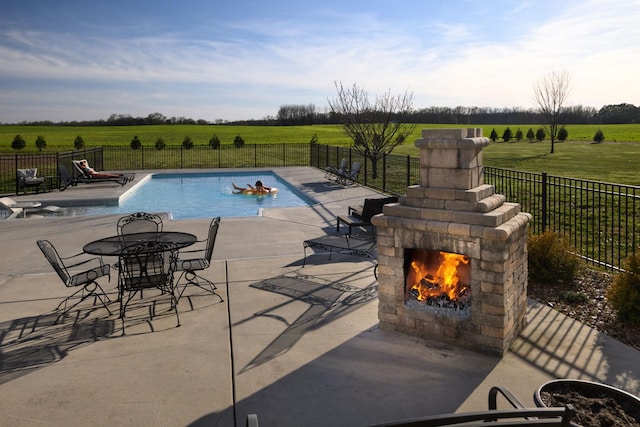 view of swimming pool featuring fence, a patio area, a rural view, and a fenced in pool